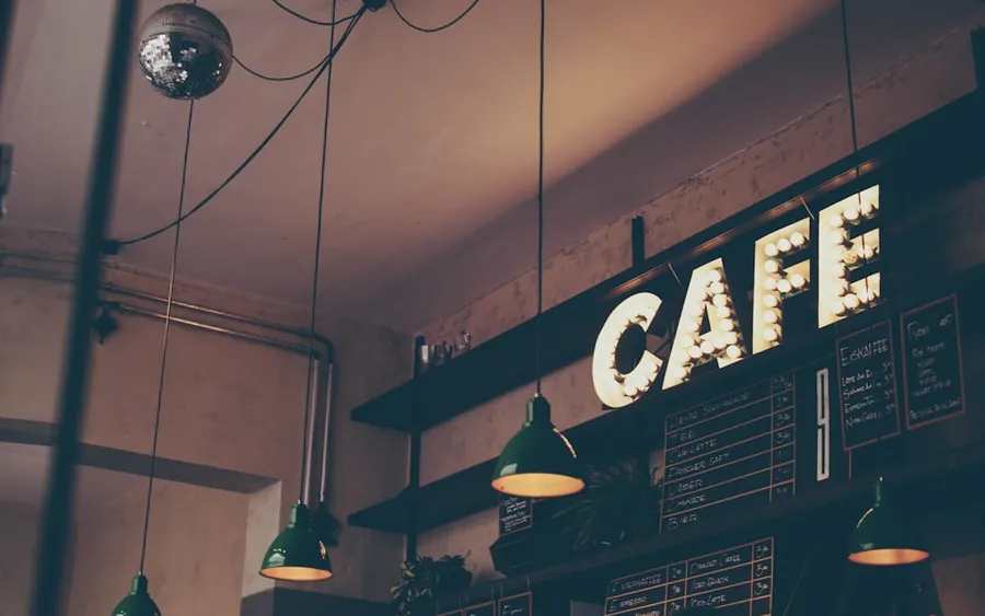 Glowing marquee CAFE sign above a neighborhood coffee bar